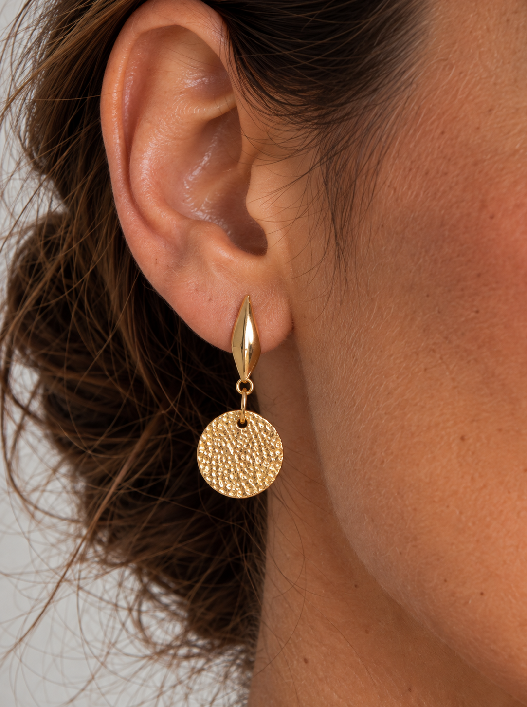 Pendientes Halo puestos en la oreja: disco dorado martillado colgando del gancho tipo gota