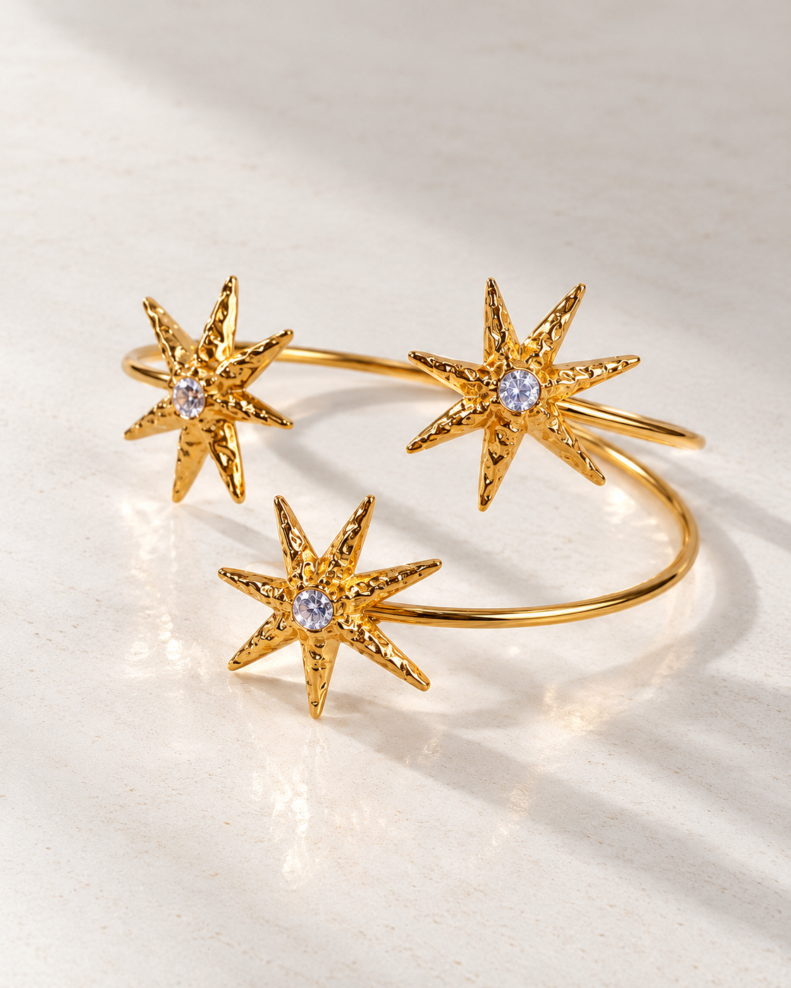 Brazalete Minerva de estrellas doradas sobre cemento blanco